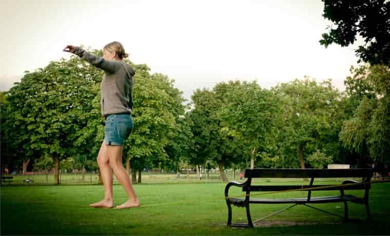 Girl walking on a slack line in the park