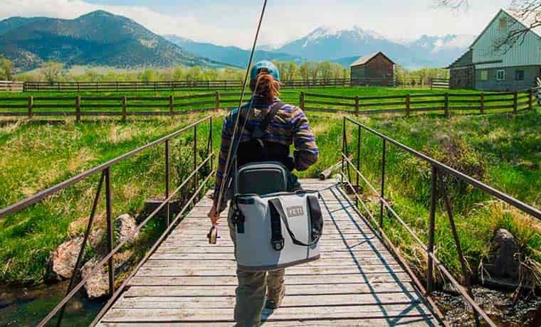 Fisherman carrying camping cooler