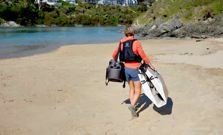 Woman walking on beach with bags
