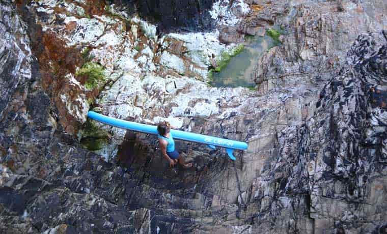 Woman walking on rocks with SUP