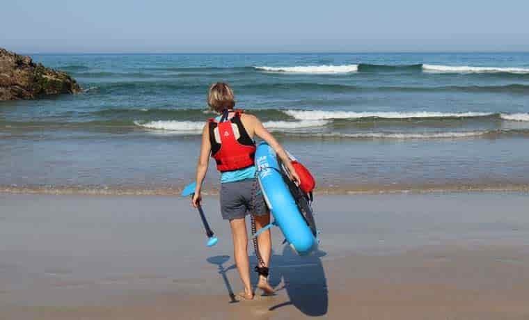 Woman walking into sea with paddle boars