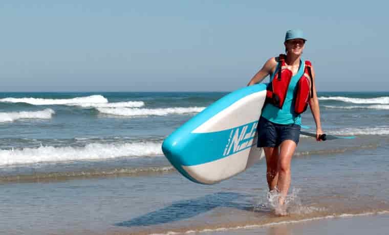 Woman walking out of sea with board