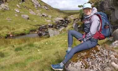 Woman hiker sitting on rock in Fjallraven eggings
