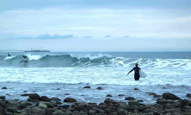 Woman walking with surfboard into the sea