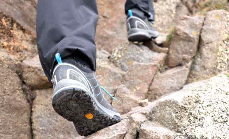 Feet in shoes climbing up rocks