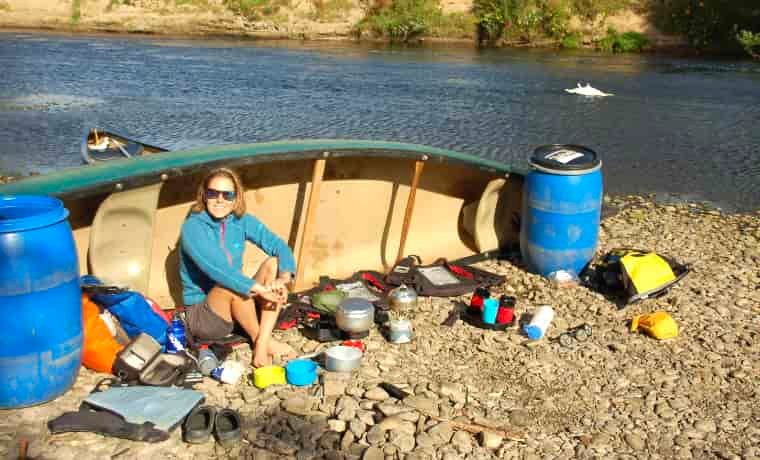 Woman cooking food next to canoe