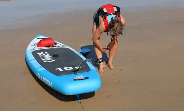 Woman putting paddle board leash on