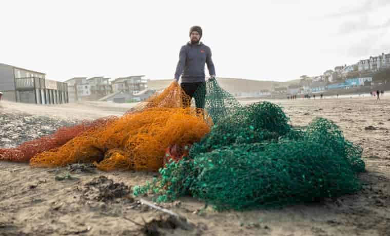 Man pulling ghost nets across the beach