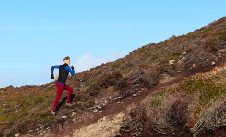 Woman running up a steep trail
