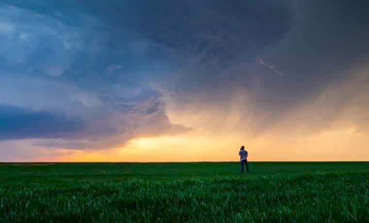 Man in field watching storm