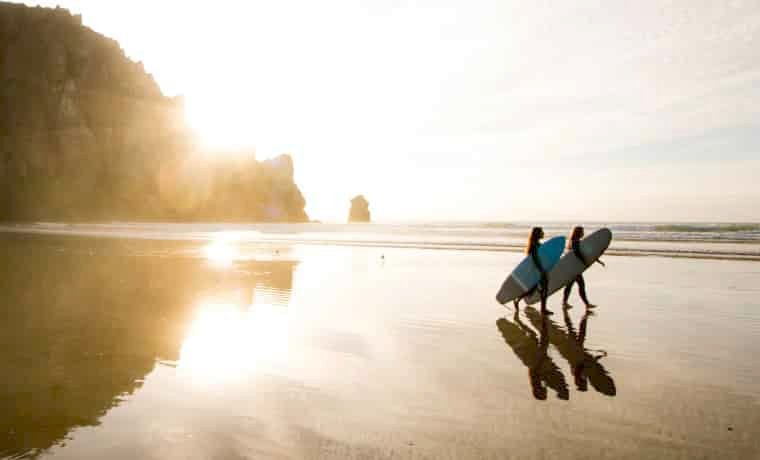 Surfers on the beach at sunset