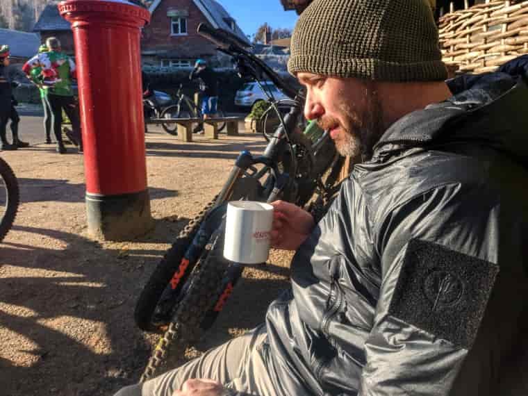 Man sitting drinking tea next to bike