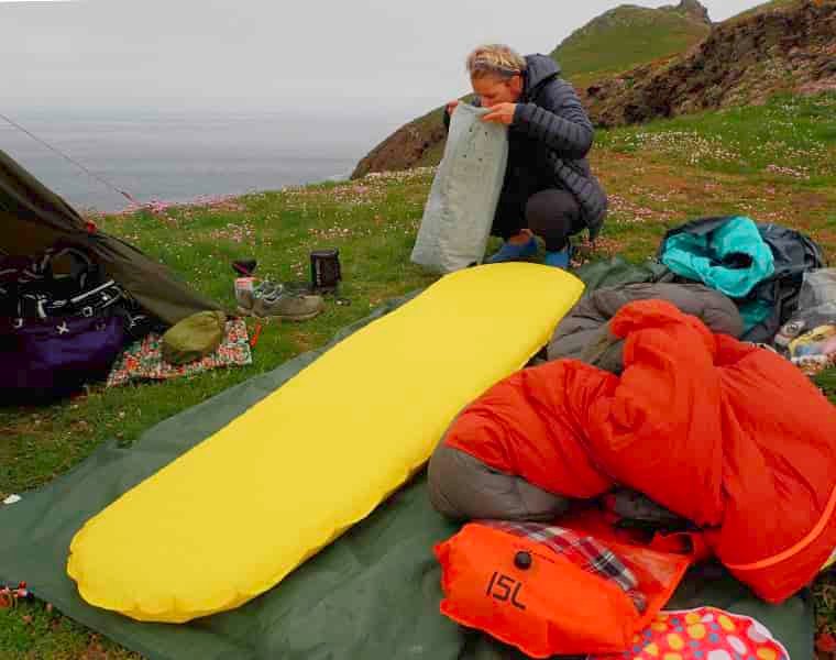 Woman using pump sack to inflate camping mattress