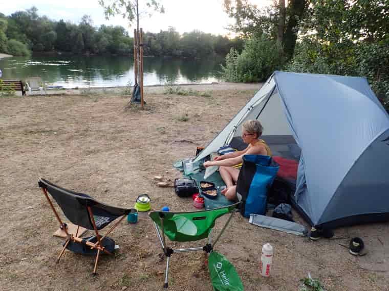 woman next to tent by lake