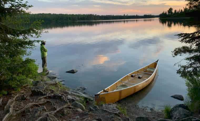 Man standing next to canoe