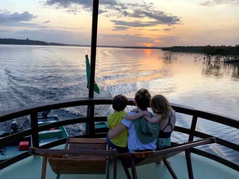 Family sitting on boat at sunset
