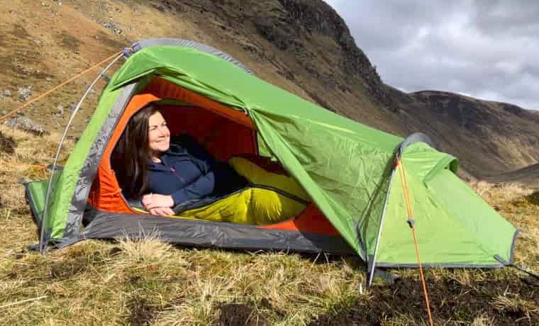 Woman camping in green tent in scotland