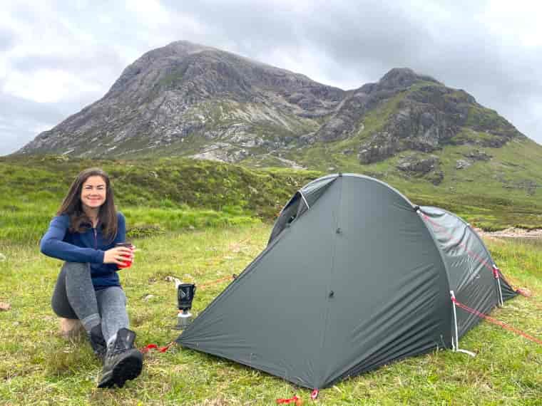 Woman sitting next to tent in Scotland