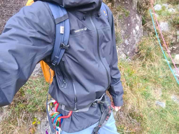 Rock climber in harness and black jacket