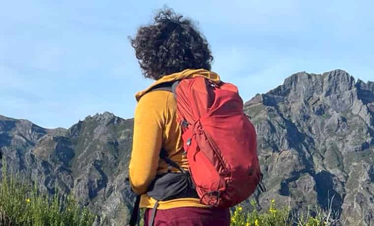 Woman with red back pack in the mountains
